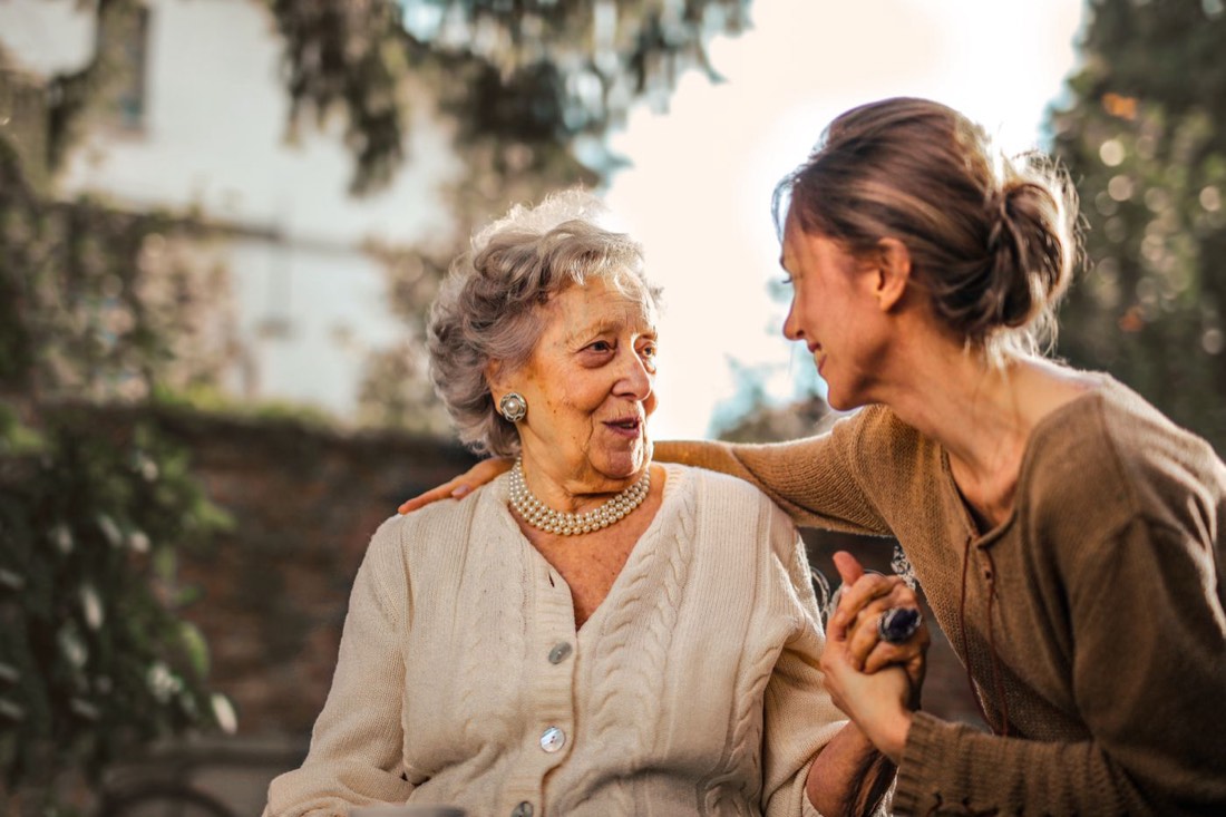 A caregiver outdoors with an older woman